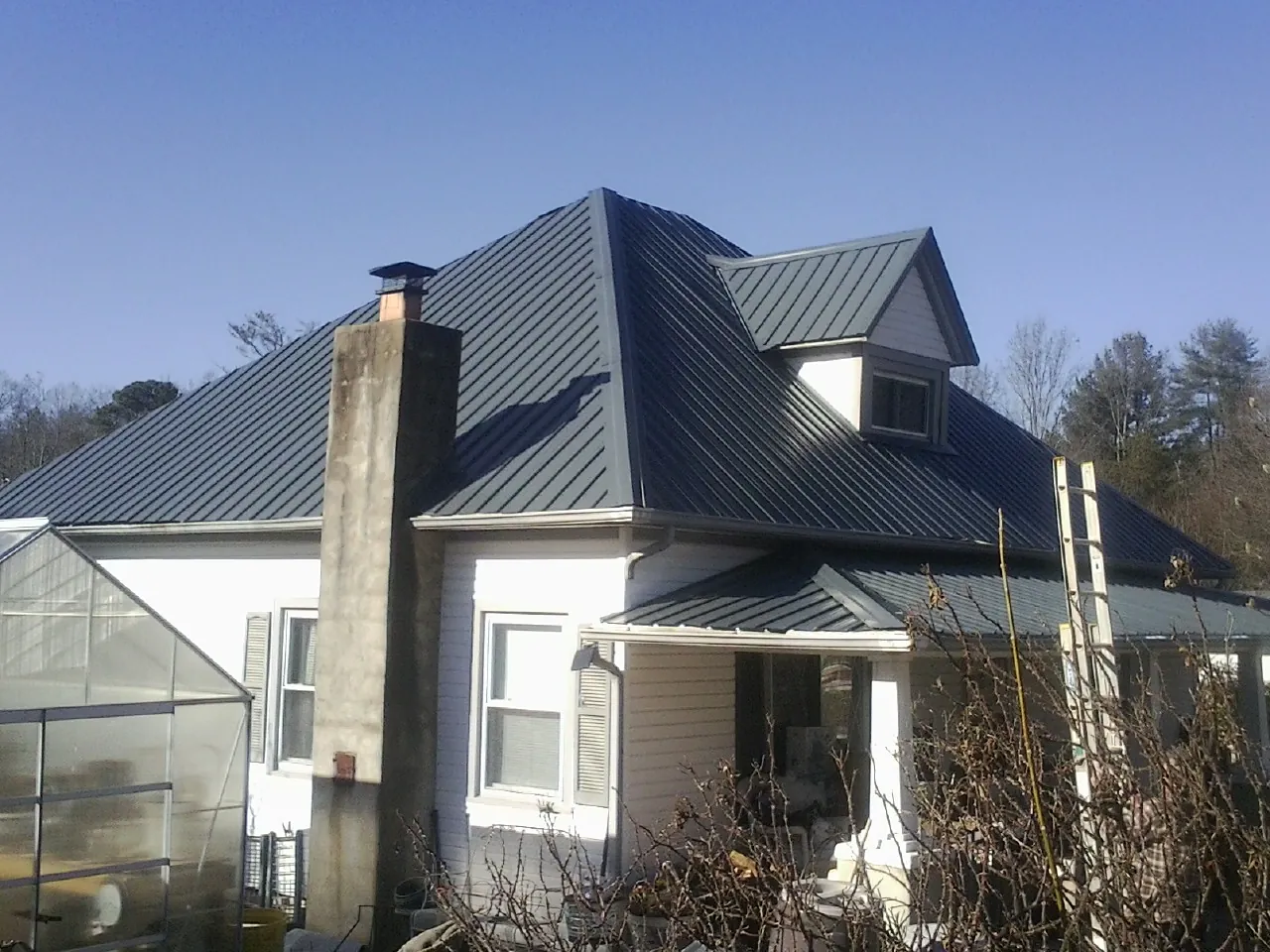Dark blue standing seam metal roof on a white farmhouse with dormer — Slate & Tile Roof Repair by Roofing Brothers in Lima