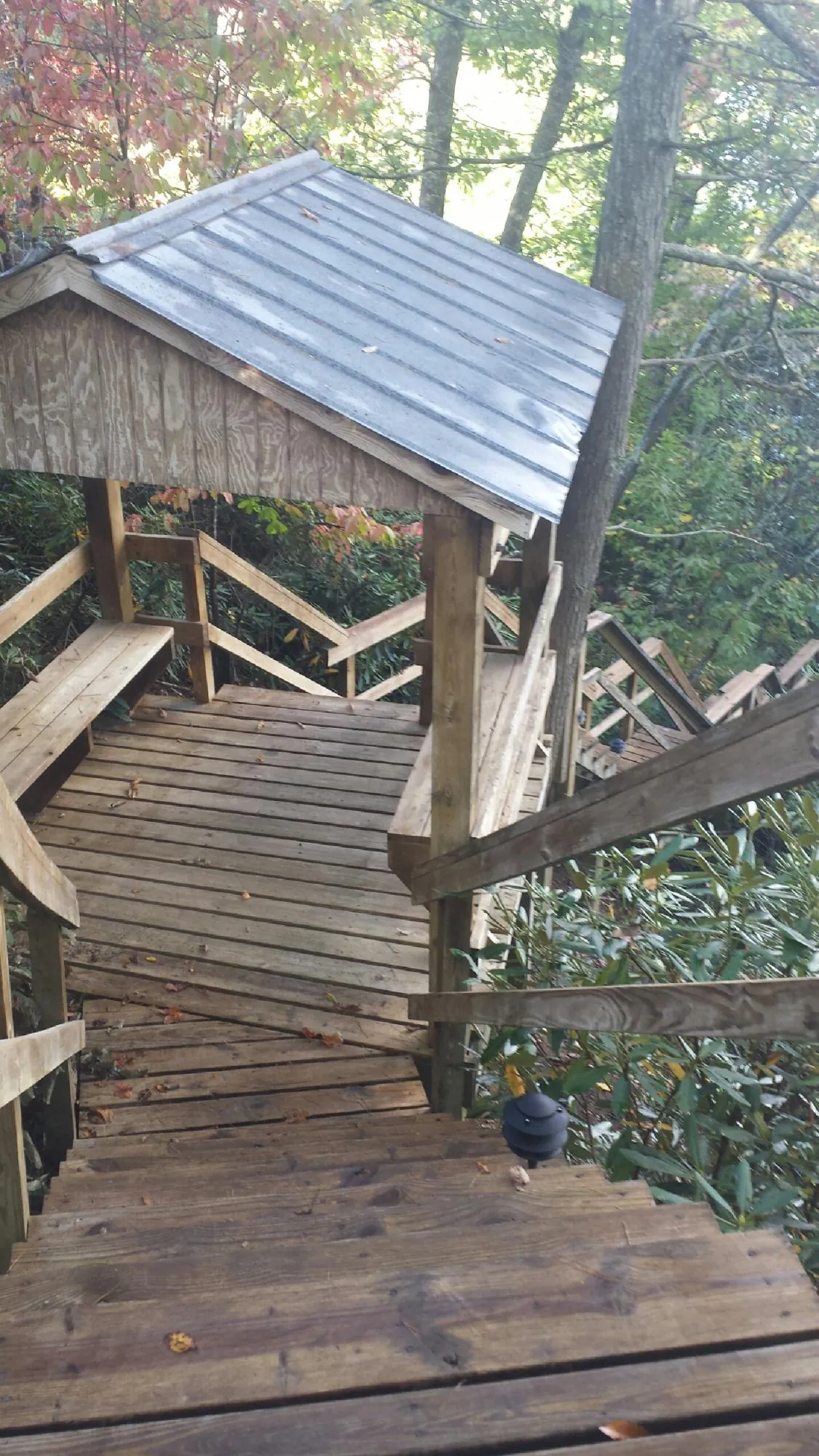 Metal roofed shelter over wooden steps on a wooded walkway — Skylight Repair & Installation work by our crew in Lima